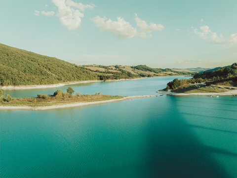 Aerial view of Lago Castreccioni surrounded by lush green hills and turquoise water in Cingoli, Marche, Italy.