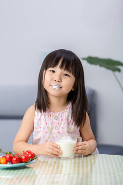 Happy Asian little girl drinking milk, healthy nutrition and calcium intake concept