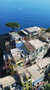 Picturesque aerial view of the village of Corniglia in Cinque Terre, Italy, showcasing colorful homes perched on a cliff overlooking the Mediterranean Sea, vertical video