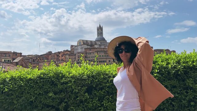 Woman enjoying the view of Siena's historic cityscape in Tuscany, Italy with view of Duomo cathedral at background