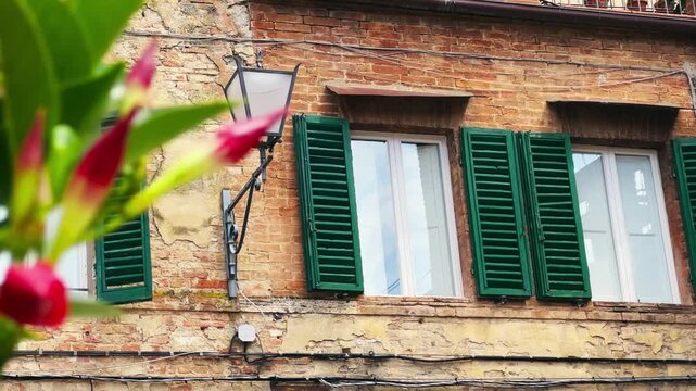 Apartment establishing shot of historic Tuscany Brick Building with Green Shuttered Windows and Vibrant Flowers
