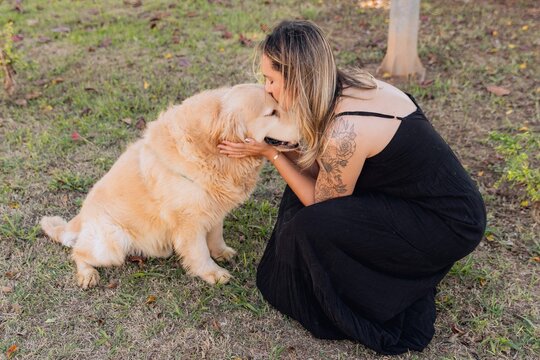 Mulher beijando um cachorro golden