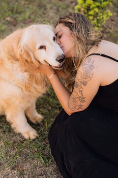 Mulher beijando um cachorro golden