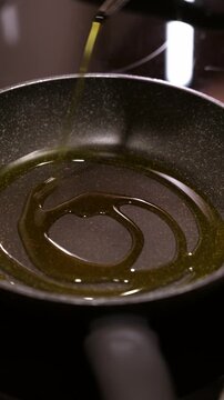 Pouring olive oil into pan on induction stove. Cooking healthy food.
