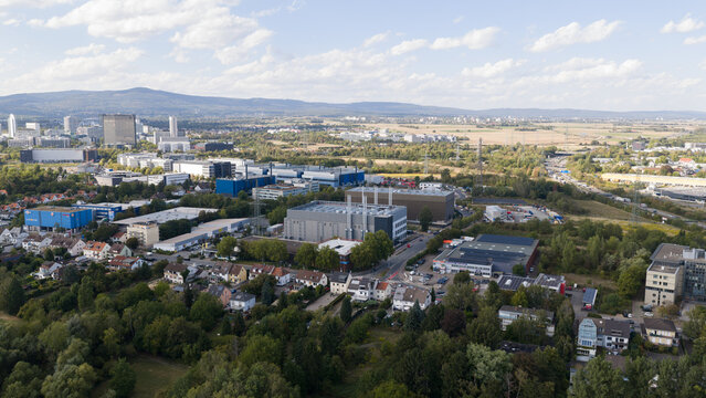 Aerial view of industrial buildings and residential houses surrounded by green trees and fields in Frankfurt am Main, Hessen, Germany.