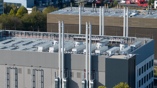 Aerial view of a modern industrial building roof featuring multiple HVAC ventilation units and tall chimneys in Frankfurt am Main, Hessen, Germany.