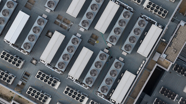 Aerial view of numerous industrial HVAC cooling units and ventilation systems arranged on a flat commercial rooftop in Frankfurt am Main, Hessen, Germany.