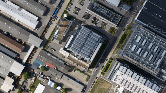 Aerial view of industrial buildings with solar panels on rooftops, parking lots, and surrounding roads in Frankfurt am Main, Hessen, Germany.