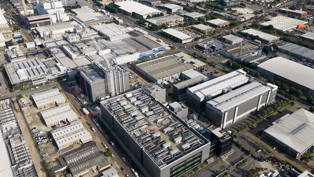 Aerial view of a large industrial data center complex with extensive rooftop HVAC cooling units, modern warehouse buildings, and surrounding infrastructure in Slough, England, United Kingdom.
