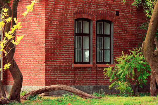 Charming brick cottage with autumn foliage and picturesque trees in the courtyard