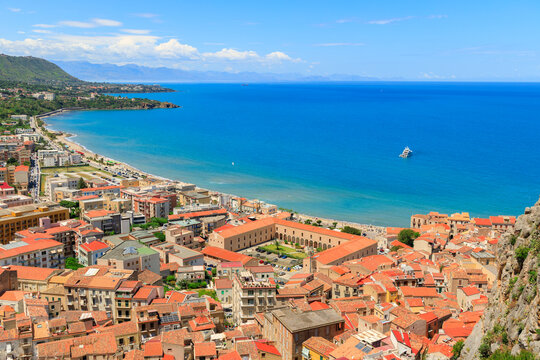 Aerial view of a coastal town with terracotta roofs and a blue sea bay