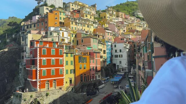 Tourist woman sightseeing colorful Riomaggiore village in Cinque Terre, Italy from a Scenic Viewpoint