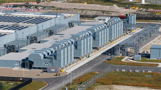 Aerial view of a large industrial facility featuring rows of cooling units, solar panels on the roof, and surrounding infrastructure in Groningen, Groningen, Netherlands.