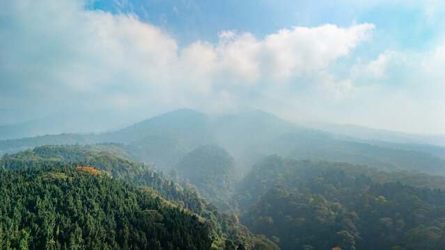 Aerial view of Mount Gede surrounded by lush green forests and misty mountain peaks in West Java, Indonesia.