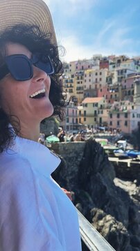Smiling stylish fashion woman enjoying her vacation in picturesque Manarola village in Cinque Terre, Italy, vertical video