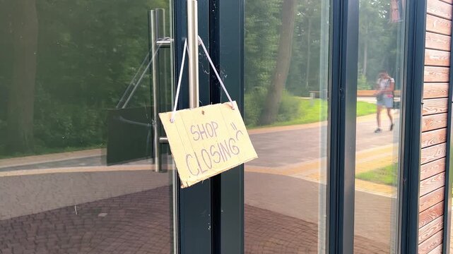 CLOSED sign hanging on small shop door. Small business shutting down due to financial crisis. Local business unable to survive economic pressure