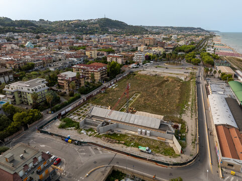 Aerial view of the Ex Stadio Fratelli Ballarin construction site with concrete structures and a crane, surrounded by the urban landscape of San Benedetto del Tronto, Marche, Italy.