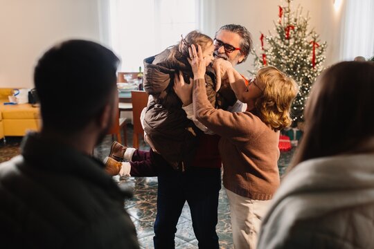 Grandparents embracing grandchild at christmas family gathering