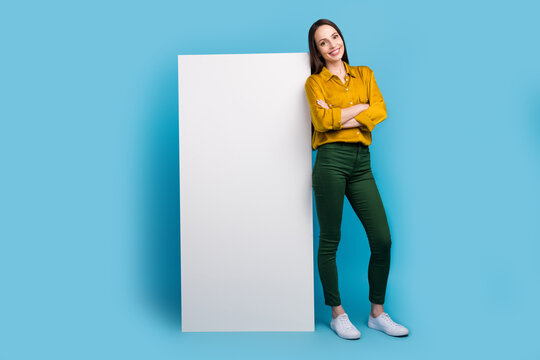 Full length photo of funky confident lady wear yellow shirt arms folded modern gadget empty space isolated blue color background