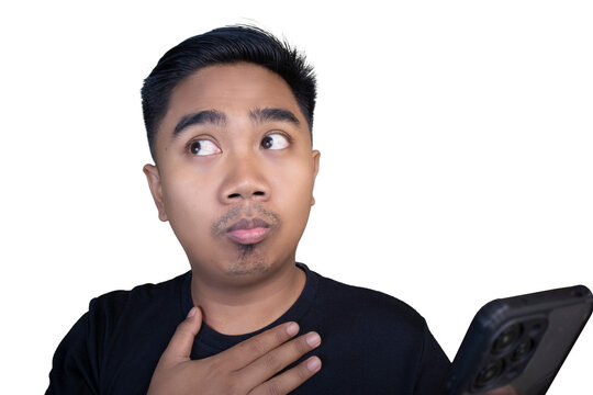 Relieved and nervous Indonesian man in a black t-shirt looking away while holding his hand on his chest with an apprehensive expression against a white background.
