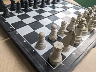 A close up view of a classic chess board with white and black pieces set up for a game. © Maslan