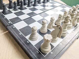 A close up view of a plastic chess set on a wooden table. © Maslan