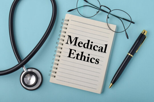 Notebook displaying medical ethics beside a stethoscope, eyeglasses, and pen on a blue background, representing healthcare professionalism, clinical responsibility
