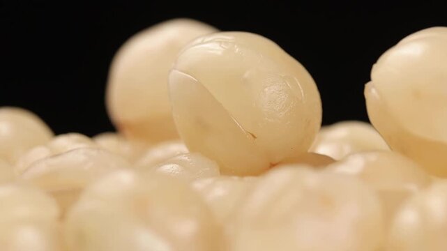 A pile of peeled longkong fruit rotating on a black background, Thai fruit.