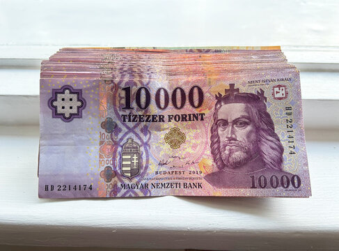Stack of Hungarian 1000 forint banknotes displayed on a light wooden surface. Hungarian currency featuring 1000 HUF notes and the portrait of King Matthias Corvinus. Close-up of Hungarian currency.