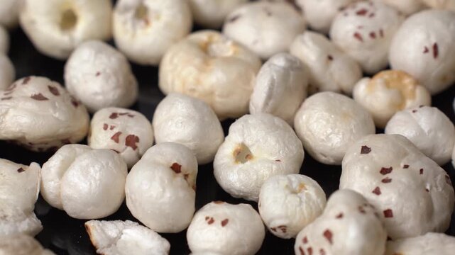 Close-up view of roasted fox nuts or gorgon nut, Euryale ferox, organic healthy vegetarian superfood snack on dark background