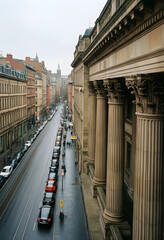 Obraz premium Urban infrastructure and city development, historic architecture with classical columns lining a busy street with parked cars and commuters in a city center