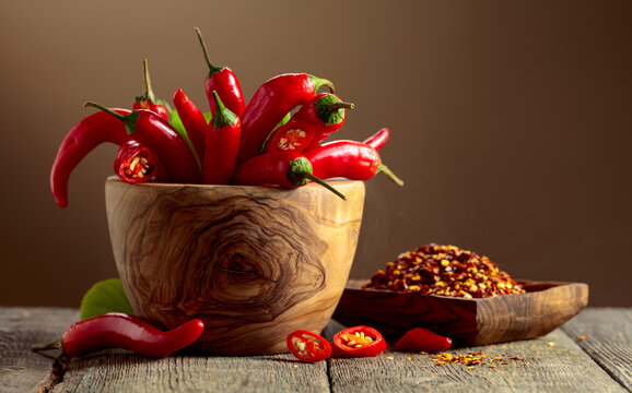 Fresh red chili peppers and dry pepper flakes on an old wooden table.
