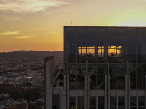 Aerial view of Unity Tower with its glass facade reflecting the golden sunset light over the cityscape of Krakow, Wojewodztwo malopolskie, Poland.