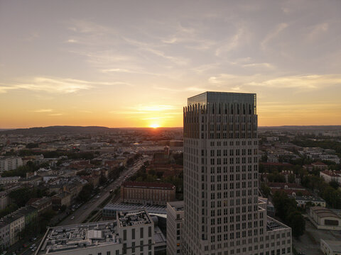 Aerial view of Unity Tower rising above the urban skyline of Krakow during a warm sunset, with city streets and buildings visible below in Krakow, Malopolskie, Poland.