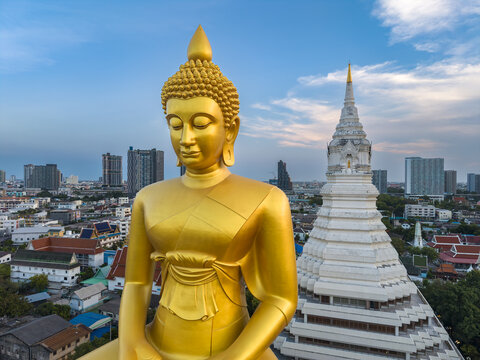 Aerial view of Wat Paknam Phasi Charoen with its large golden Buddha statue and white stupa set against the Bangkok cityscape in Bangkok, Krung Thep Maha Nakhon, Thailand.