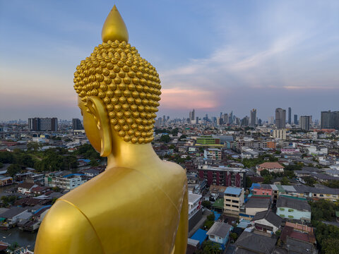 Aerial view of the giant golden Buddha statue at Wat Paknam Phasi Charoen overlooking the dense urban cityscape of Bangkok, Krung Thep Maha Nakhon, Thailand.