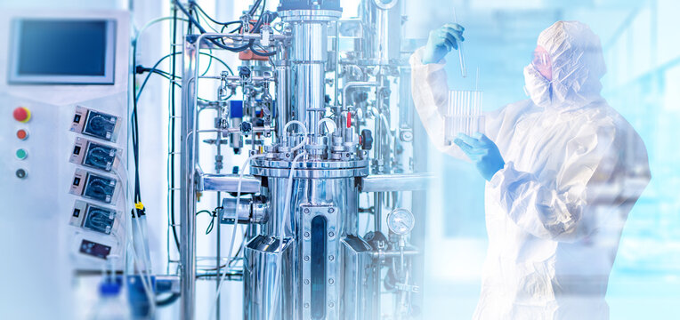 Biopharmaceutical manufacturing, laboratory technician analyzes samples beside a bioreactor during biotechnology research, testing and production.