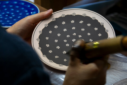 Close-up of a round plate with black glaze background and a repeating white plum blossom dot pattern, Kyushu region, Arita, Japan