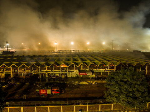 Aerial view of a fire burning at the airport terminal building at night with thick smoke rising and a fire truck parked nearby in Dhaka, Dhaka Division, Bangladesh.