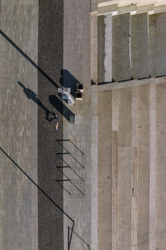 Aerial view of a person walking on a paved walkway next to stone steps and bike racks in Wroclaw, Lower Silesian Voivod, Poland.