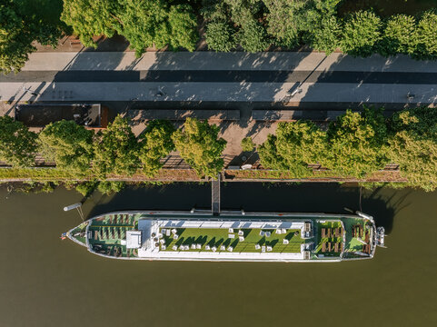 Aerial view of a river boat docked along the tree-lined banks of the Oder River in Wroclaw, Lower Silesian Voivodeship, Poland.