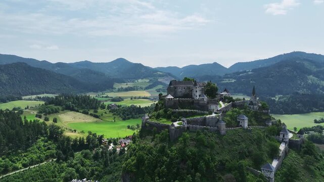 Cinematic drone footage capturing Hochosterwitz Castle on hilltop, fortified walls, dramatic cliffs, summer colors, sweeping aerial movement, historical landmark atmosphere