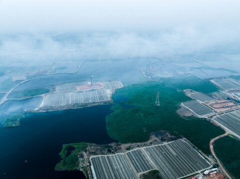 Aerial view of the industrial landscape in Aminbazar, featuring brick kilns and water bodies under a misty sky in Aminbazar, Dhaka Division, Bangladesh.