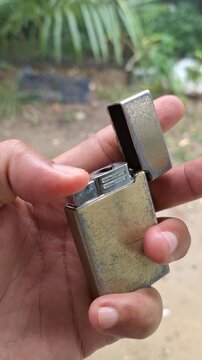 Close-up of a hand holding a vintage metal flip lighter outdoors for troubleshooting, repair, and lifestyle concept