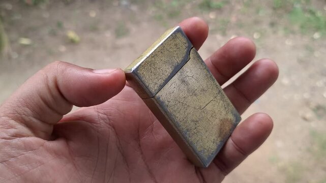 Close-up of a vintage metal lighter mechanism with refill valve exposed in hand for repair, troubleshooting, and maintenance concept