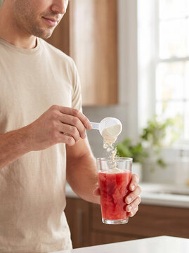 Fit guy preparing a pre-workout drink or dietary supplement at home