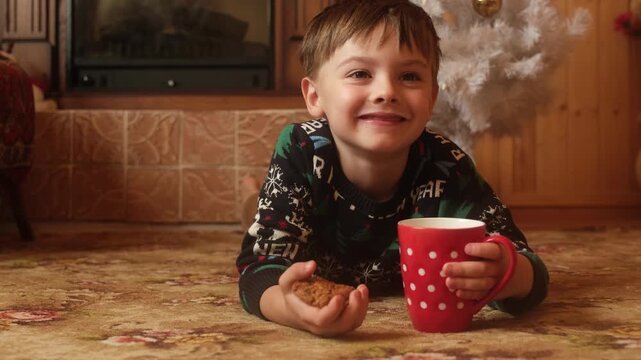 Small boy drinking milk with cookies on Christmas Eve in a cozy house 