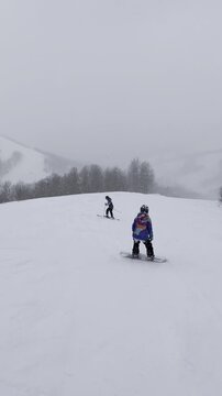 Video of a snowboarder riding down a slope. Live footage of a snowboarder on a snow-covered run. A calm descent.