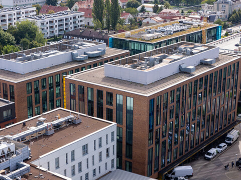 Aerial view of modern brick office buildings with large windows and rooftop HVAC units in an urban district in Gdansk, Poland.