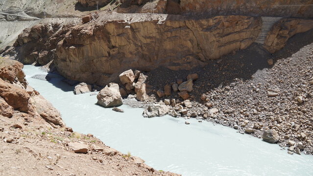 Rugged river flowing through the rocky canyon of lungnak valley with turquoise water of tsarap river and brown cliffs enroute Phugtal monastery in zanskar, India
